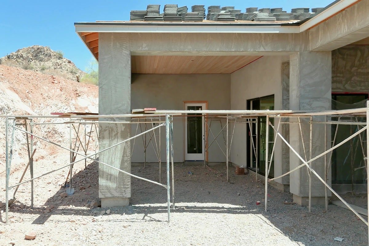 Back patio of an Arizona home mid-build, with scaffolding and roof tile staged, documented on a site visit