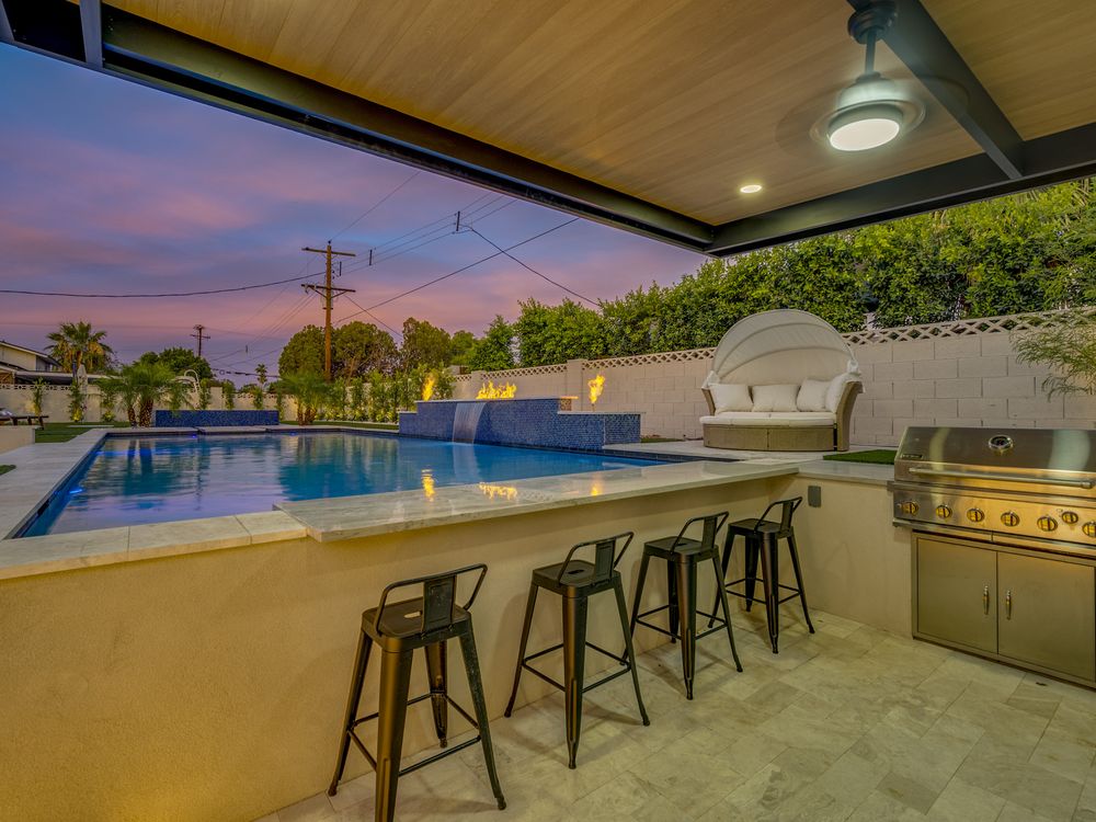 Outdoor kitchen and bar beside a lit pool at twilight, Scottsdale